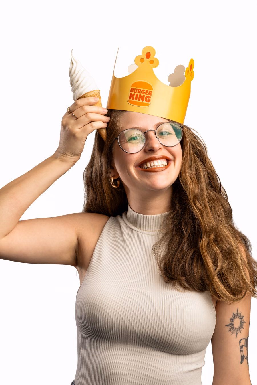 Colaboradora com a coroa do Burger King na mão; em seguida, a foto troca e aparece com a coroa na cabeça e uma casquinha